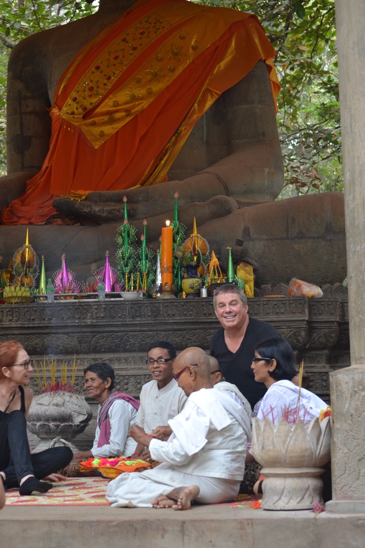 Steve Bender and new glasses wearers seated beneath a large robed Buddha statue