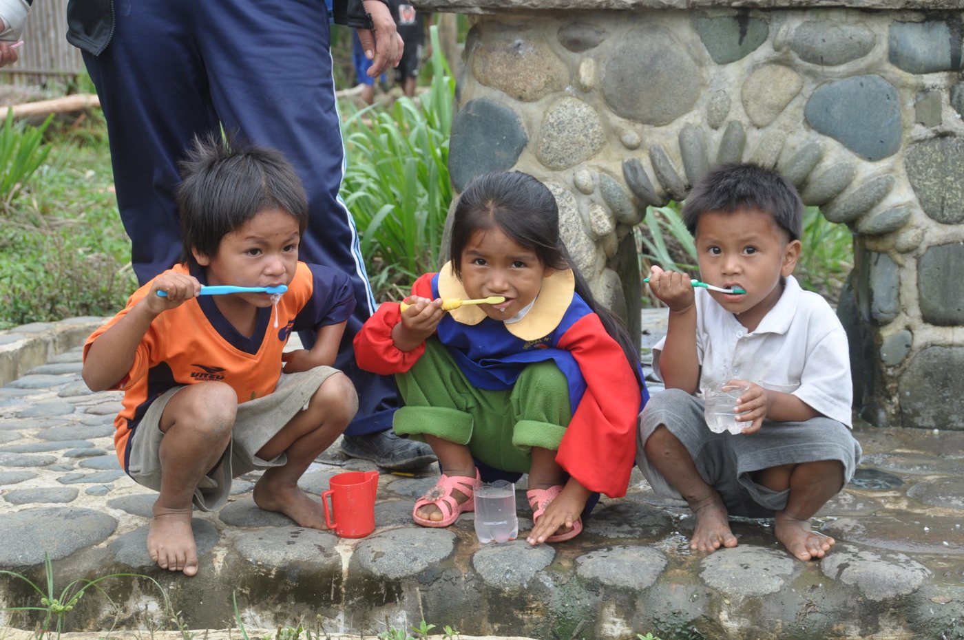Three young children in Peru brush their teeth with new toothbrushes