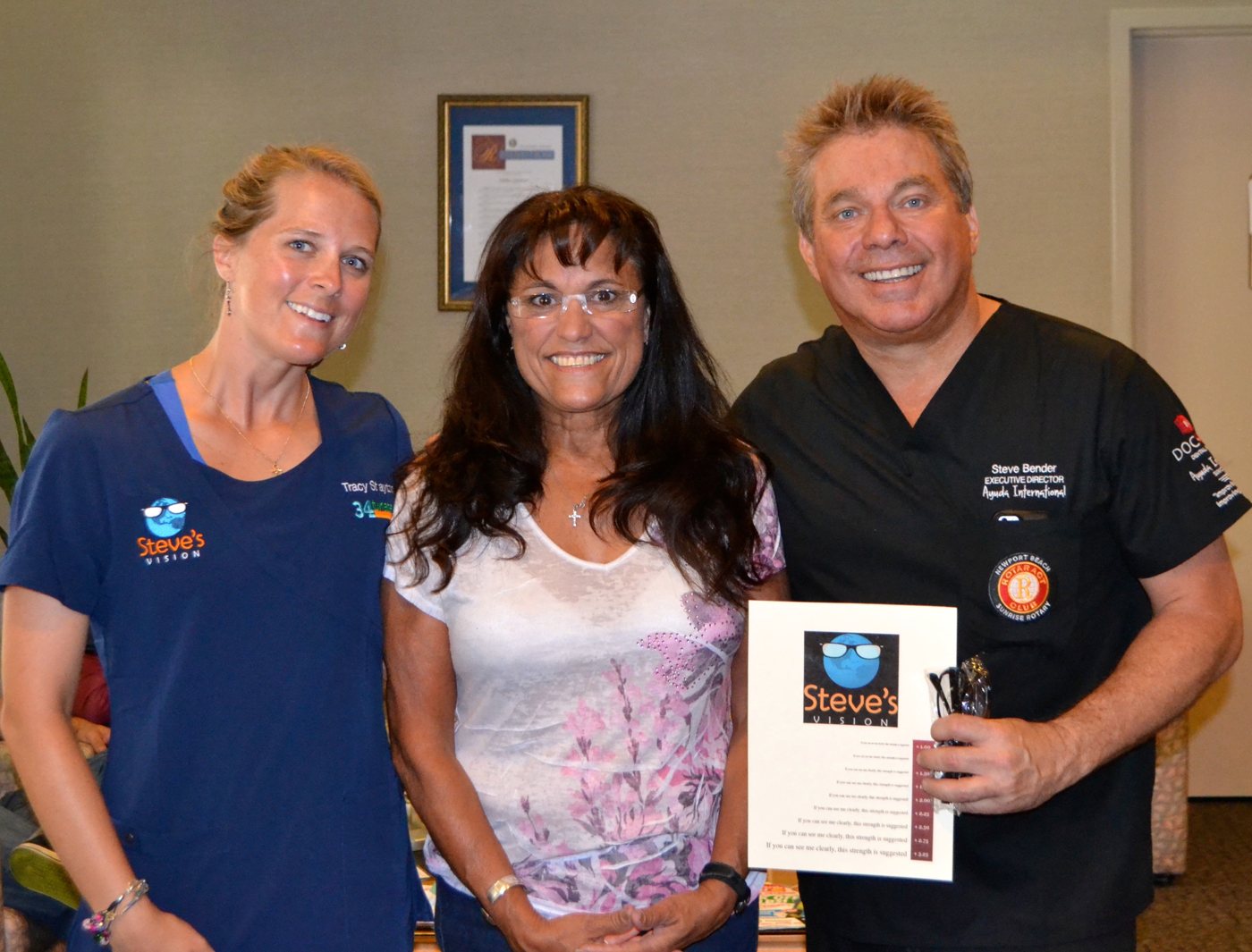 Steve Bender, volunteer Tracy Stayton in Steve's Vision scrubs, and a smiling woman in her new rimless readers, with the Steve's Vision strength card